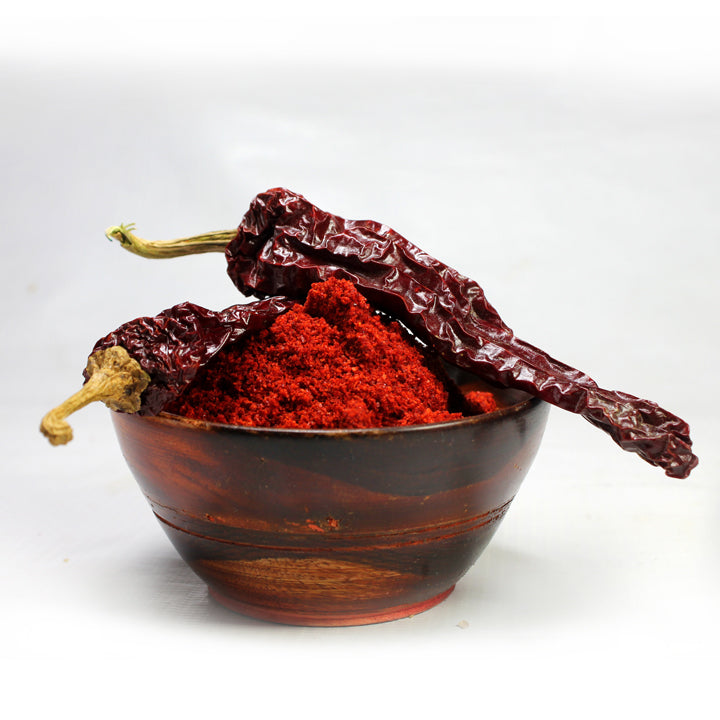 Dabbi Byadgi chilli powder in a wooden bowl with dried red chillies, showcasing the rich red colour and natural homemade texture of Mantra Herbs spice.